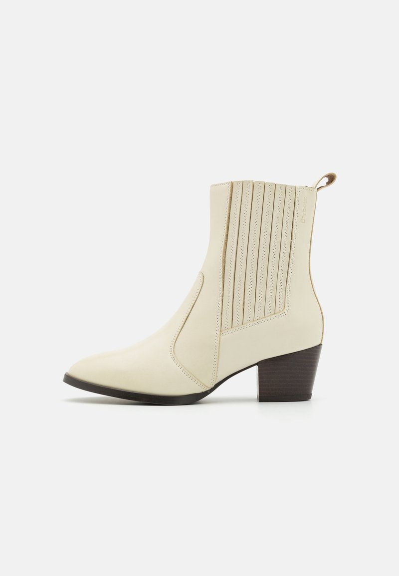 Bottine en cuir crème avec talon superposé, panneaux latéraux élastiques et languette à l'arrière, présentée de profil sur fond blanc.