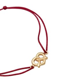 Röd snörarmband med en polerad gul metalldäpp som har ett sammanflätat knutdesign. Däppet är präglat med "925" för silverinnehåll.