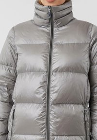 Zilveren opblaasjack met een hoge kraag, voorzien van gestikte secties, een centrale rits en zijzakken met stijlvolle metalen hardware.