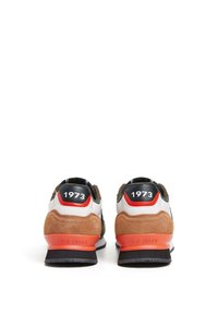 Idrottsskor med en blandning av material: mocka och nät i grått, vitt och olivgrönt, med orange detaljer och en svart hälflik märkt "1973."