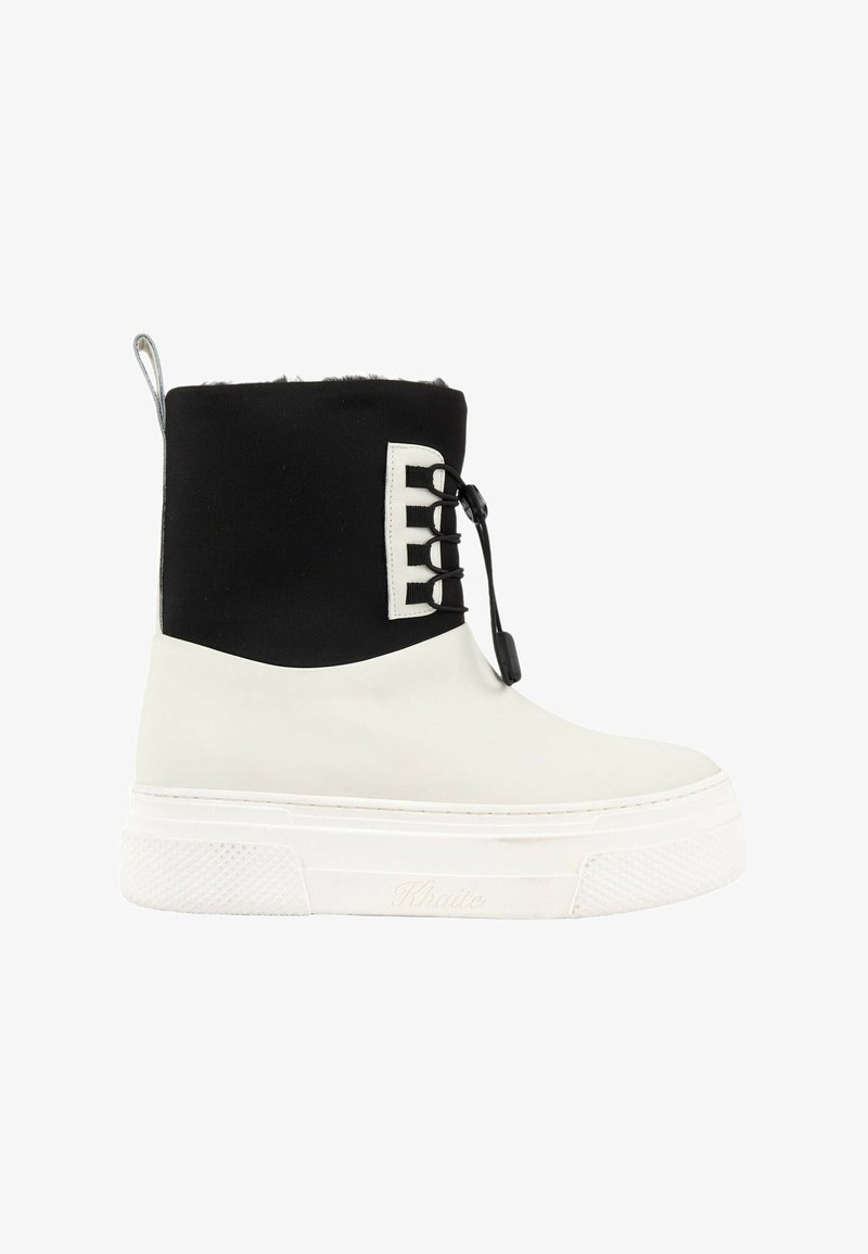 Bottine montante de type sneaker avec semelle et partie inférieure en caoutchouc blanc, dessus noir avec œillets pour lacets et languette à l'arrière.