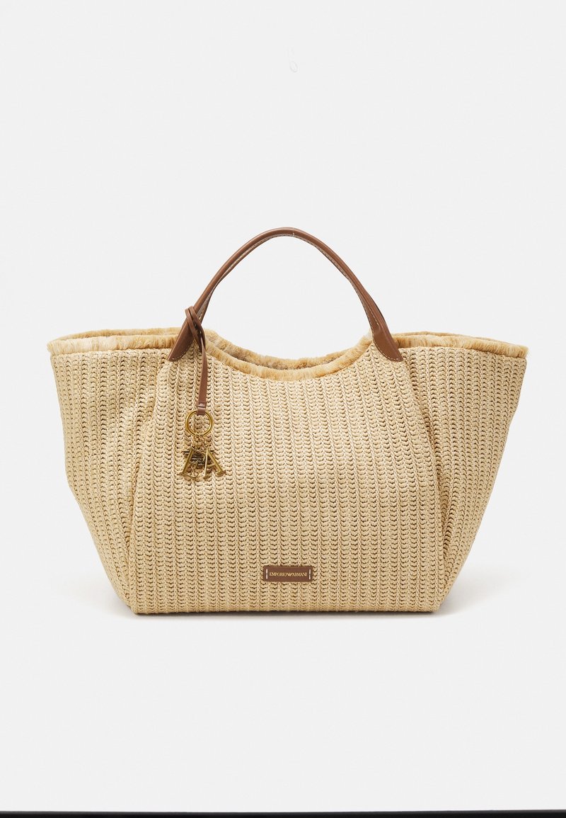 Beige woven straw tote bag with brown leather handles. Features a keychain accent and a structured shape, ideal for casual use.