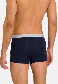 Boxers bleu marine avec une taille élastique grise arborant le nom de la marque. Le tissu paraît lisse et ajusté au corps.