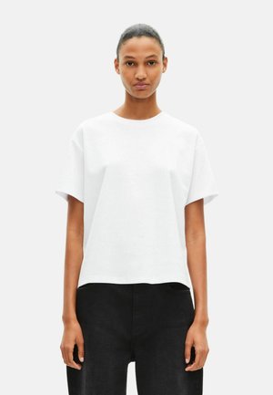 Witte T-shirt met korte mouwen, ronde hals en een relaxte pasvorm, gemaakt van een soepel materiaal. Gecombineerd met zwarte, hoog gebouwde broek.