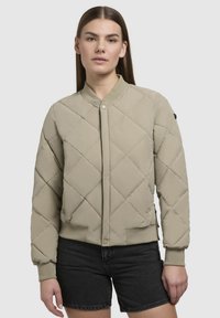 Beige gewatteerde bomberjack met ribbed manchetten en kraag, voorzien van een frontale drukknoopsluiting en subtiele zijritszakken.