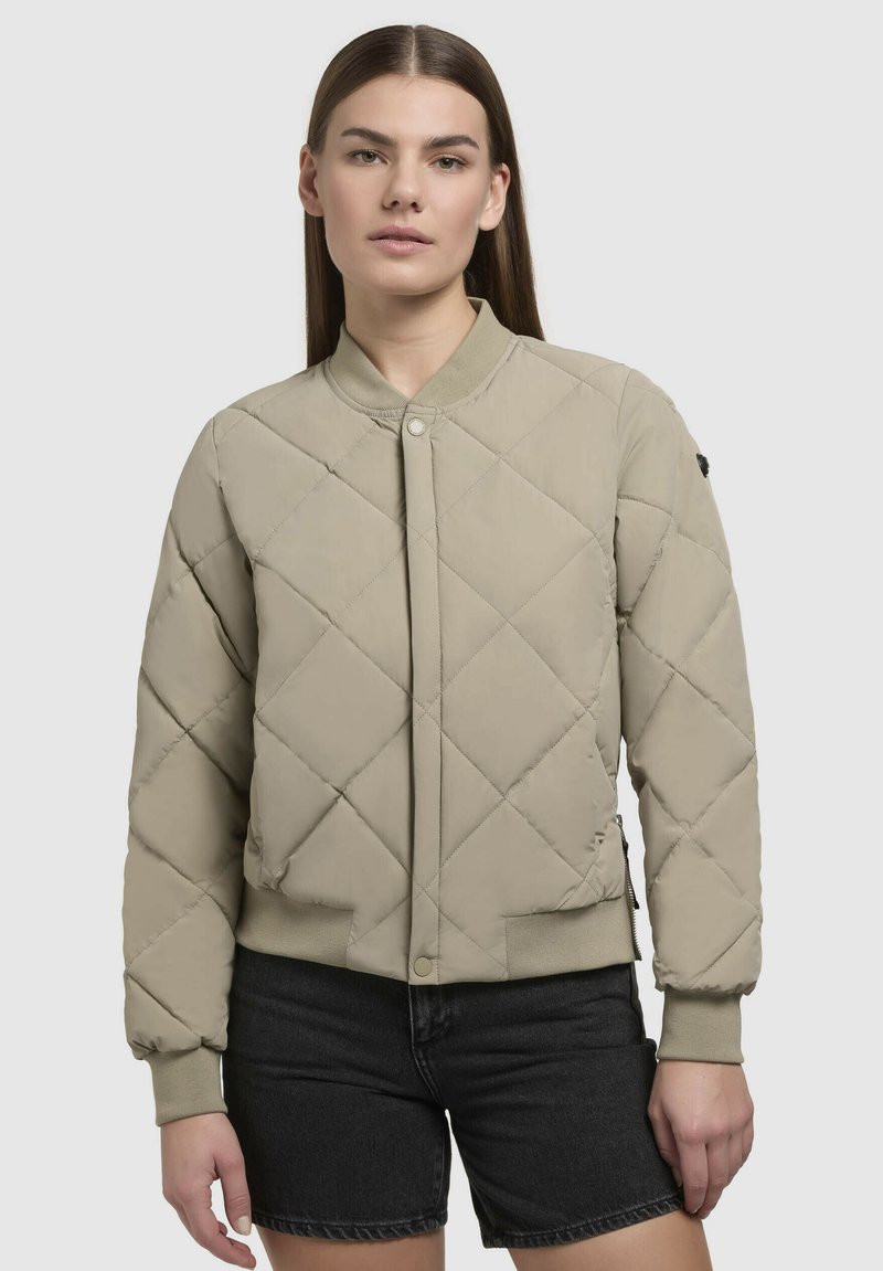 Beige gesteppte Bomberjacke mit gerippten Bündchen und Kragen, ausgestattet mit einem Druckknopfverschluss auf der Vorderseite und dezenten seitlichen Reißverschlusstaschen.