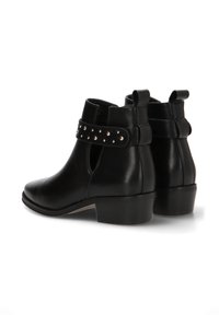 Botines de cuero negro hasta el tobillo con punta redonda, correa con patrón que presenta tachuelas plateadas y un tacón bajo en bloque.