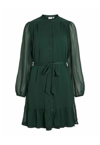 Rochie verde închis, până la genunchi, cu închidere cu nasturi, manșete elastice și cordon la talie. Are mâneci transparente și un tiv volanat.