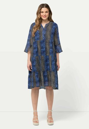 Blaues und schwarzes gemustertes Kleid aus weichem, transparentem Stoff, mit drei Viertel-Ärmeln, rundem Ausschnitt und gestuftem Saum. Die Länge reicht bis oberhalb des knies.