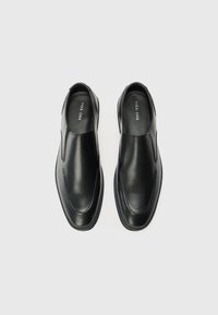 Czarne skórzane buty wsuwane o gładkiej fakturze, zaokrąglonym nosku i przeszyciach po bokach. Minimalistyczny design bez elementów metalowych.