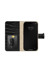 Svart telefonlommebokveske med krokodillemønster og beige innside, som holder et kort og en iPhone i lukket posisjon, med en uttrekksflik.