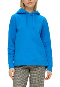 Felblau hoodie van zacht materiaal, met een trekkoordcapuchon, lange mouwen en een ontspannen pasvorm. Gecombineerd met zwarte en witte gebloemde broek.