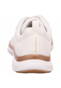 White and tan Skechers athletic shoe heel with textured sole and pull tab, shown from the back on a white background.