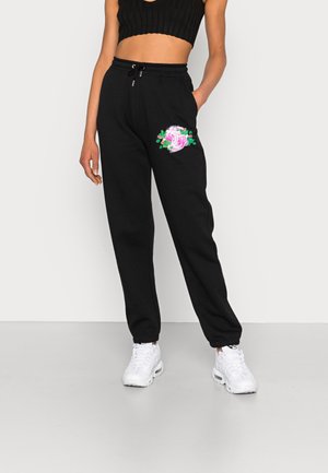 Zwarte sweatpants met een geborduurd rozenontwerp op de linkerzak, voorzien van een trekkoord in de tailleband en taps toelopende boorden.