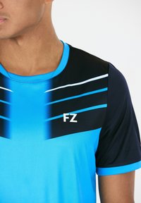 Blå sportt-shirt med svarta detaljer, horisontella ränder i olika nyanser av blått och en vit "FZ"-logotyp på bröstet. Slät textur.