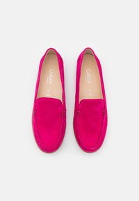 Růžové suede loaferky s plochým podpatkem, s prošívanými detaily podél okrajů a hladkým vnitřním podšívkou. Logo značky viditelné uvnitř.