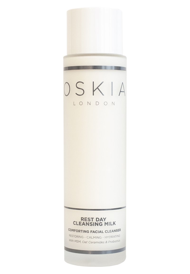 Hvid flaske med mat finish, sort tekst og cylindrisk form. Etiketten siger "REST DAY CLEANSING MILK" med produktdetaljer nedenfor.