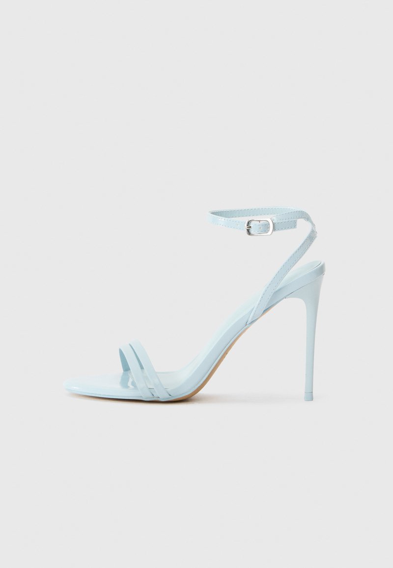 Sandalia de tacón stiletto azul claro con dos correas frontales y correa en el tobillo, hecha de material patent suave, con un tacón delgado y diseño minimalista.