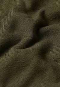 Tessuto verde oliva con una superficie morbida e testurizzata e una leggera rigatura. Il materiale è liscio e si drappeggia in modo naturale, mostrando delicate pieghe.