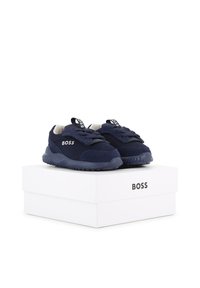 Baskets BOSS bleu marine avec lacets posées sur une boîte blanche portant la marque BOSS sur le côté.