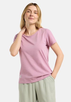 Lichtroze T-shirt met korte mouwen, gemaakt van zachte stof, met een ronde halslijn en een klein logo-label aan de zoom, gecombineerd met losse groene broeken.