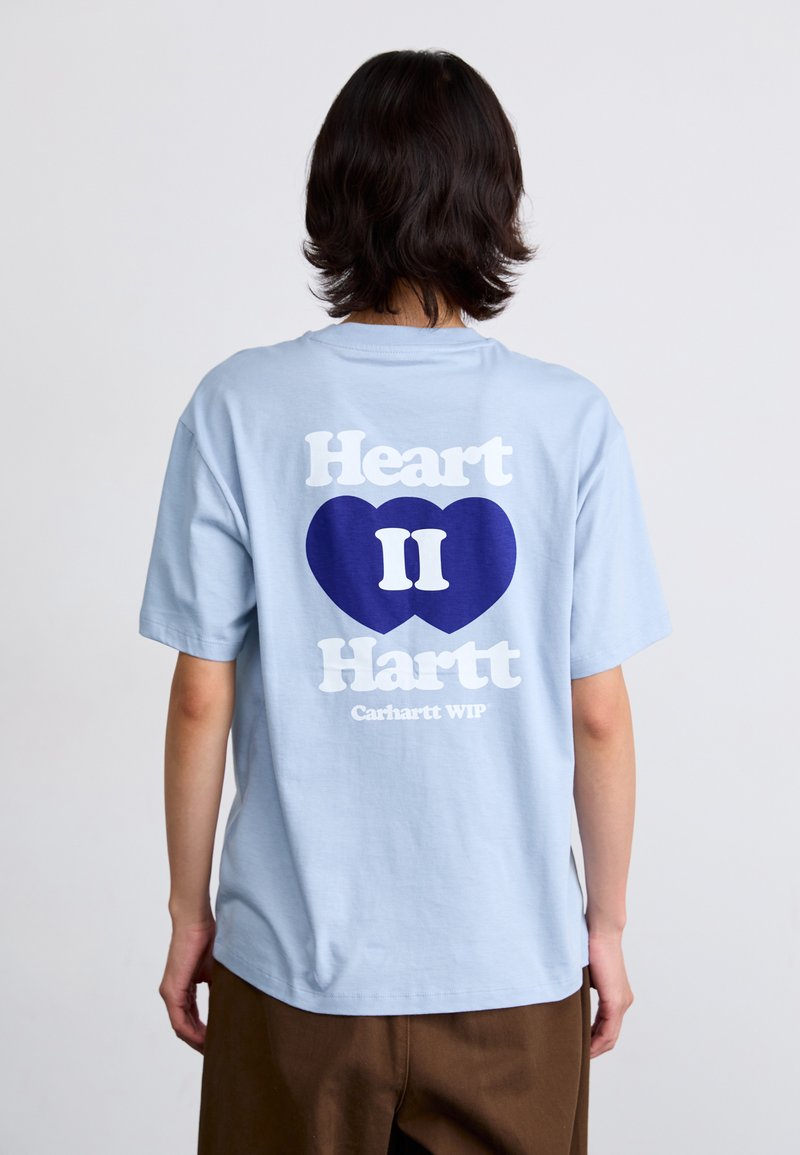 Light blue cotton t-shirt featuring a large white and navy graphic on the back with "Heart II Hartt" and "Carhartt WIP" text.