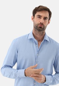 Camicia a maniche lunghe azzurro chiaro realizzata in tessuto morbido, con colletto alla francese, bottoni frontali e polsini con bottone.