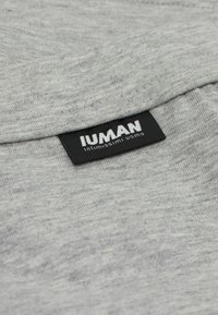 Tissu en coton gris au toucher doux, avec une étiquette noire portant les inscriptions "IUMAN" et "intimissimi uomo" en texte blanc.