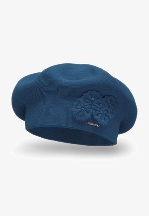 Blå strikket baret med en struktureret overflade, prydet med blomsterapplikation og en lille metal logo detaljer.