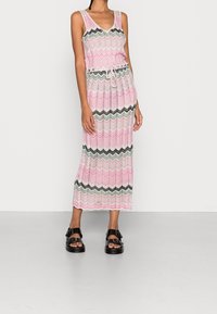 Maxiklänning med V-ringning, med ett zickzackmönster i rosa, grönt och svart. Tillverkad av ett lätt tyg och har en dragsko i midjan.