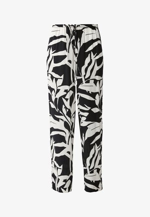 Pantalones de patrón de hojas en blanco y negro con un ajuste relajado, cintura con cordón y bolsillos laterales, combinados con una camiseta sin mangas negra de canalé y sandalias.