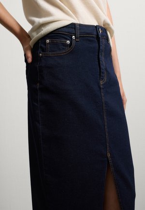 Jupe en denim bleu foncé avec une fente avant, ornée de coutures contrastantes orange et de poches avant, conçue avec une taille haute et une silhouette ajustée.