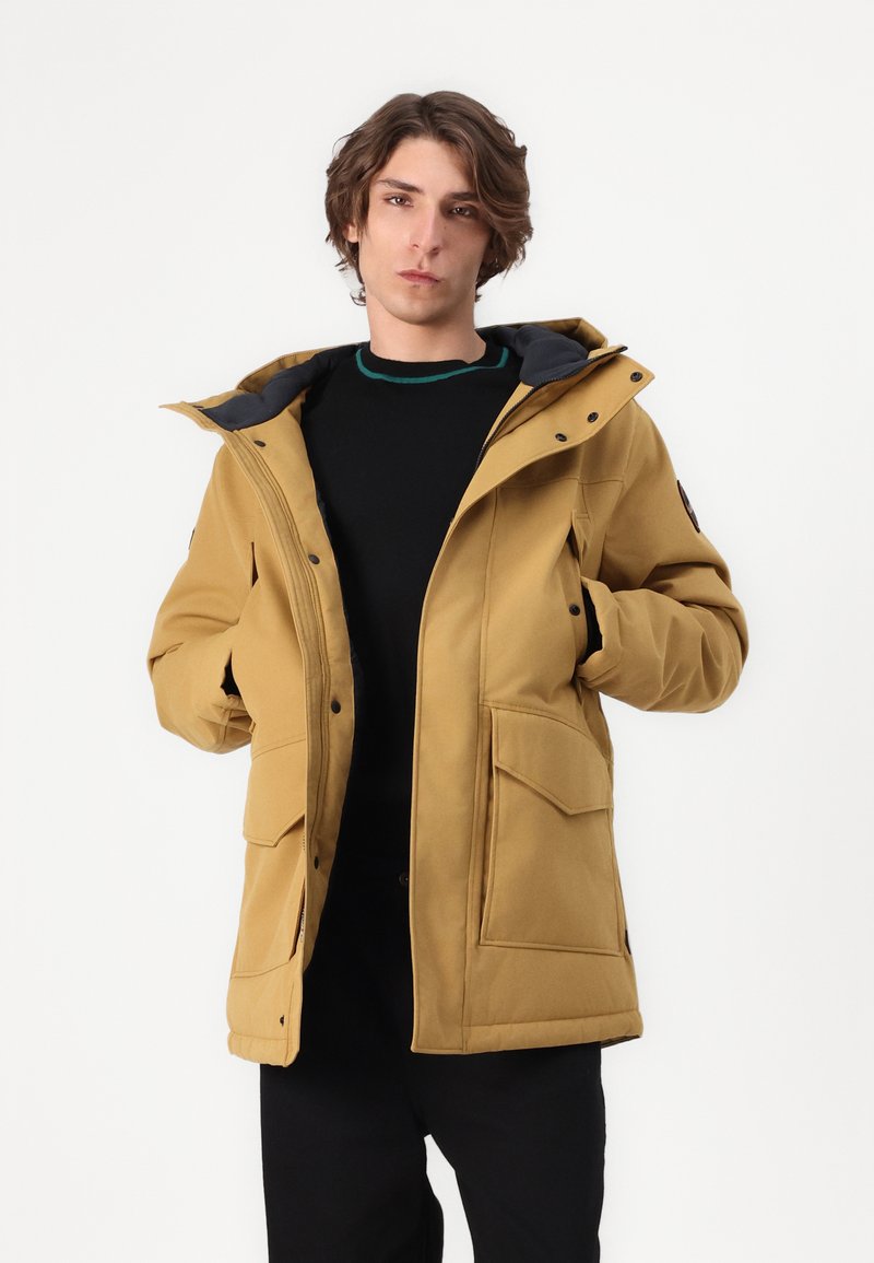 Abrigo acolchado amarillo con un alto cuello, forro interior negro y dos bolsillos frontales. Posee un diseño de cierre de cremallera y presión para mayor calidez.