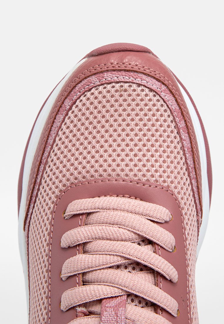 Zapatilla deportiva rosa con parte superior de malla, acentos de cuero suave, punta redonda y un cordón prominente. Entresuela blanca con rayas en contraste.