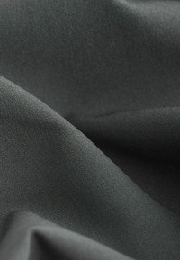 Textureret stof i en mørkegrå farve, der har en blød, glat overflade med et vævet mønster, som fremhæver dets fleksible, draperende egenskaber.