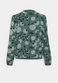 Pull vert à manches longues avec motif de vignes feuillues noires et grappes de fleurs blanches rondes, vu de dos.