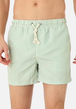 Mann trägt hellgrüne und weiß vertikal gestreifte Badehosen mit weißem Kordelzug, der an der Taille zu einem Knoten gebunden ist.