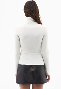 Biała, prążkowana bluzka z golfem i długimi rękawami, zestawiona z czarną, mini spódnicą z ekologicznej skóry. Teksturowany materiał i dopasowany krój.