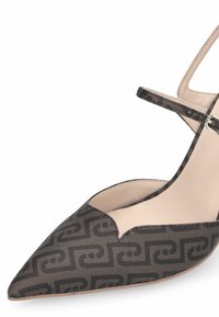 Chaussure à talon à bout pointu en matériau texturé noir avec un motif géométrique et un intérieur beige. Elle est dotée d'une fine bride de cheville avec une boucle argentée.