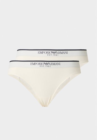 Deux sous-vêtements style bikini beige avec des bandes élastiques blanches à la taille, avec des bords noirs, et le logo ainsi que le texte Emporio Armani.