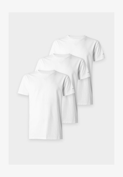 Τρία απλά λευκά T-shirt με κοντά μανίκια και στρογγυλή λαιμόκοψη, διατεταγμένα επικαλυπτόμενα πάνω σε ανοιχτό γκρι φόντο.