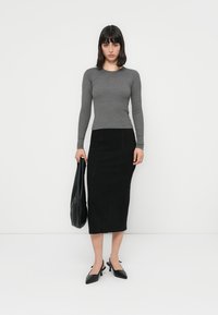 Gray long-sleeve top paired with a black fitted midi skirt. Black pointed-toe heels and a black tote bag complete the look.