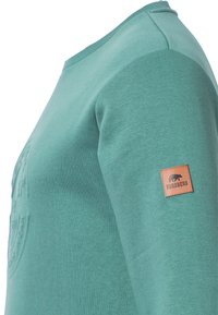 Groene sweatshirt met lange mouwen en een textuurafwerking, voorzien van een leren patch met het label "Forsberg" op de linkermouw.