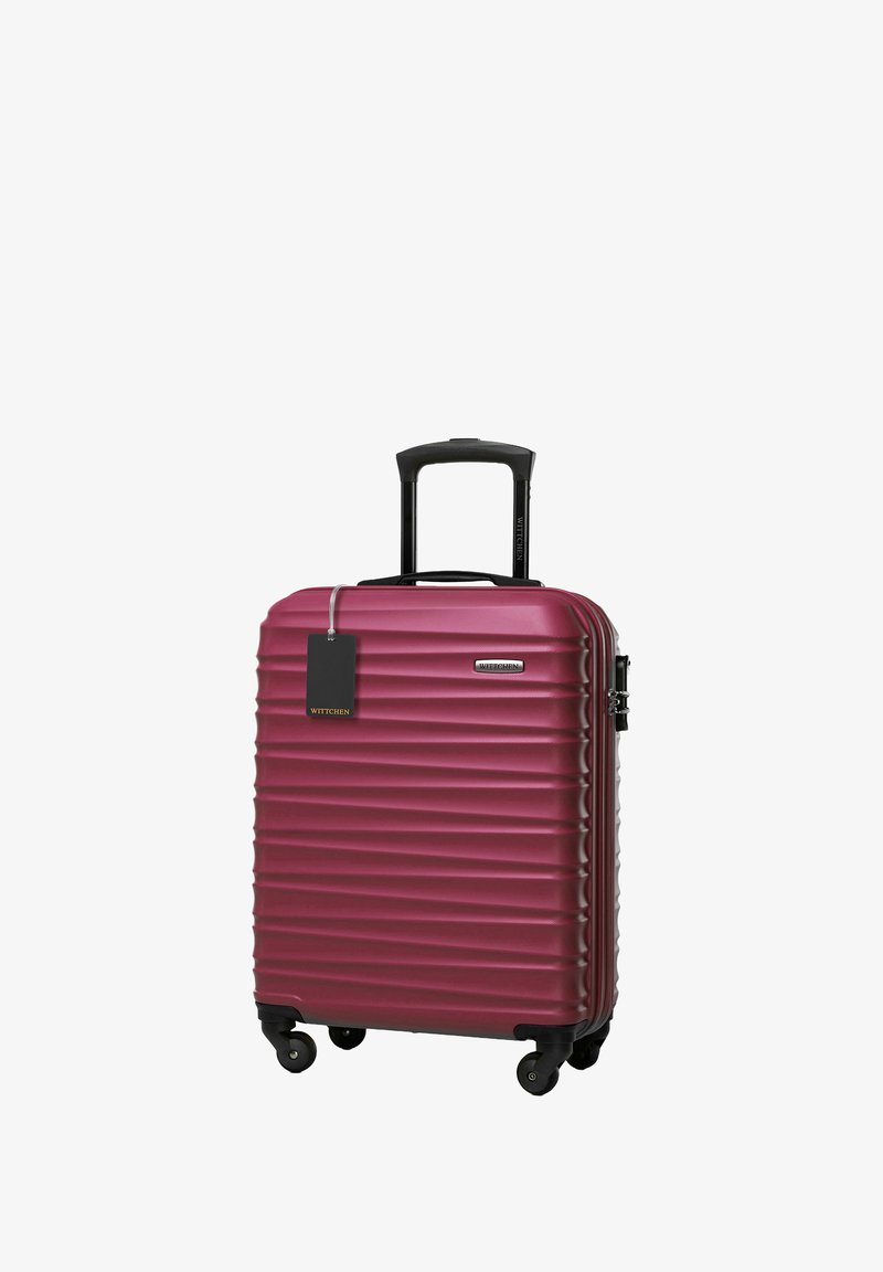 Hartschalen-Handgepäckkoffer in tiefem Burgunderrot mit gerippter Textur, schwarzem Griff, vier drehbaren Rädern und einem angehängten Gepäcktag.