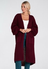 Bordowy kardigan z dzianiny z długimi, bufiastymi rękawami, otwartym przodem i dwoma przednimi kieszeniami. Żebrowana struktura, luźny, swobodny krój.