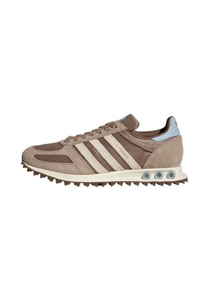 Bruine Adidas sneaker met witte strepen, getextureerde zool met gripnoppen en blauwe hieltab met veters en suède accenten.