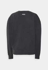Felpa nera con scollo a girocollo, maniche lunghe e polsini a costine. Presenta un piccolo logo "HUGO" sul retro. Tessuto morbido.