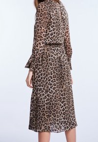 Jurk met luipaardprint, lange mouwen, een slanke pasvorm en een vloeiende silhouet. Gemaakt van licht, semi-transparant materiaal.