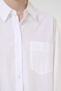White cotton button-up shirt with a pointed collar, single chest pocket, and smooth texture. Includes six button closures down the front.