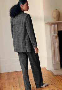 Tmavě šedý kostkovaný blazer a kalhoty, přiléhavý střih, strukturovaná látka, jednopropínací blazer, kalhoty s volným střihem, s jemnými akcenty.